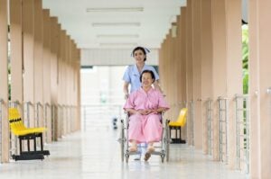 thai nurse pushing old woman in wheel chair
